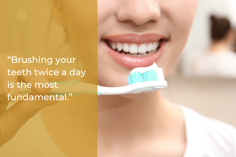 A person smiling while holding a toothbrush near their teeth; text on the image emphasizes brushing twice a day as essential for oral health and healthy gums.