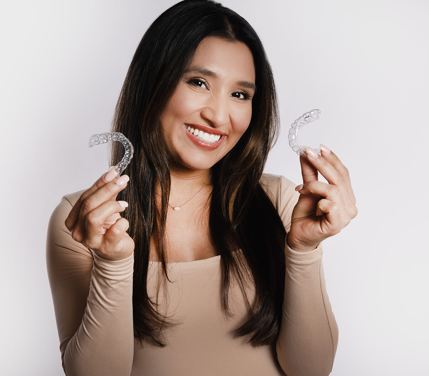 Smiling patient holding CandidPro clear aligners